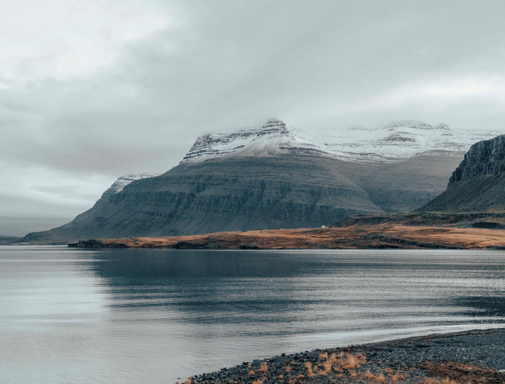 Scenic black mountains contrasting the ocean, crowned with snow-covered peaks, creating a striking coastal landscape