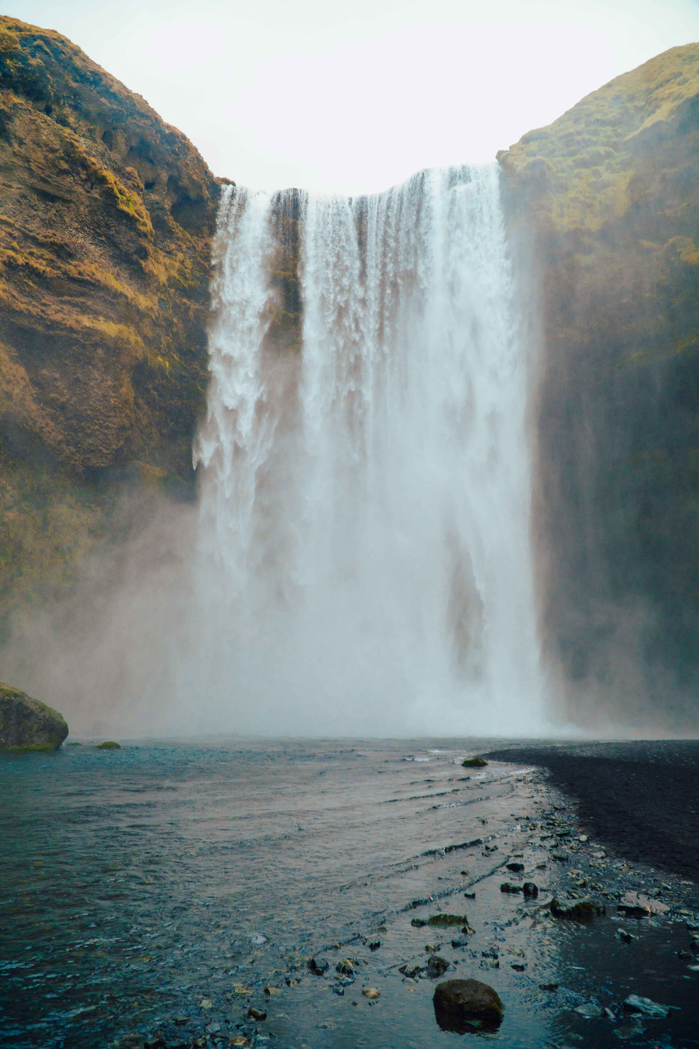 Skógafoss: A majestic waterfall showcasing vibrant contrasts of blue and green in its cascading waters.