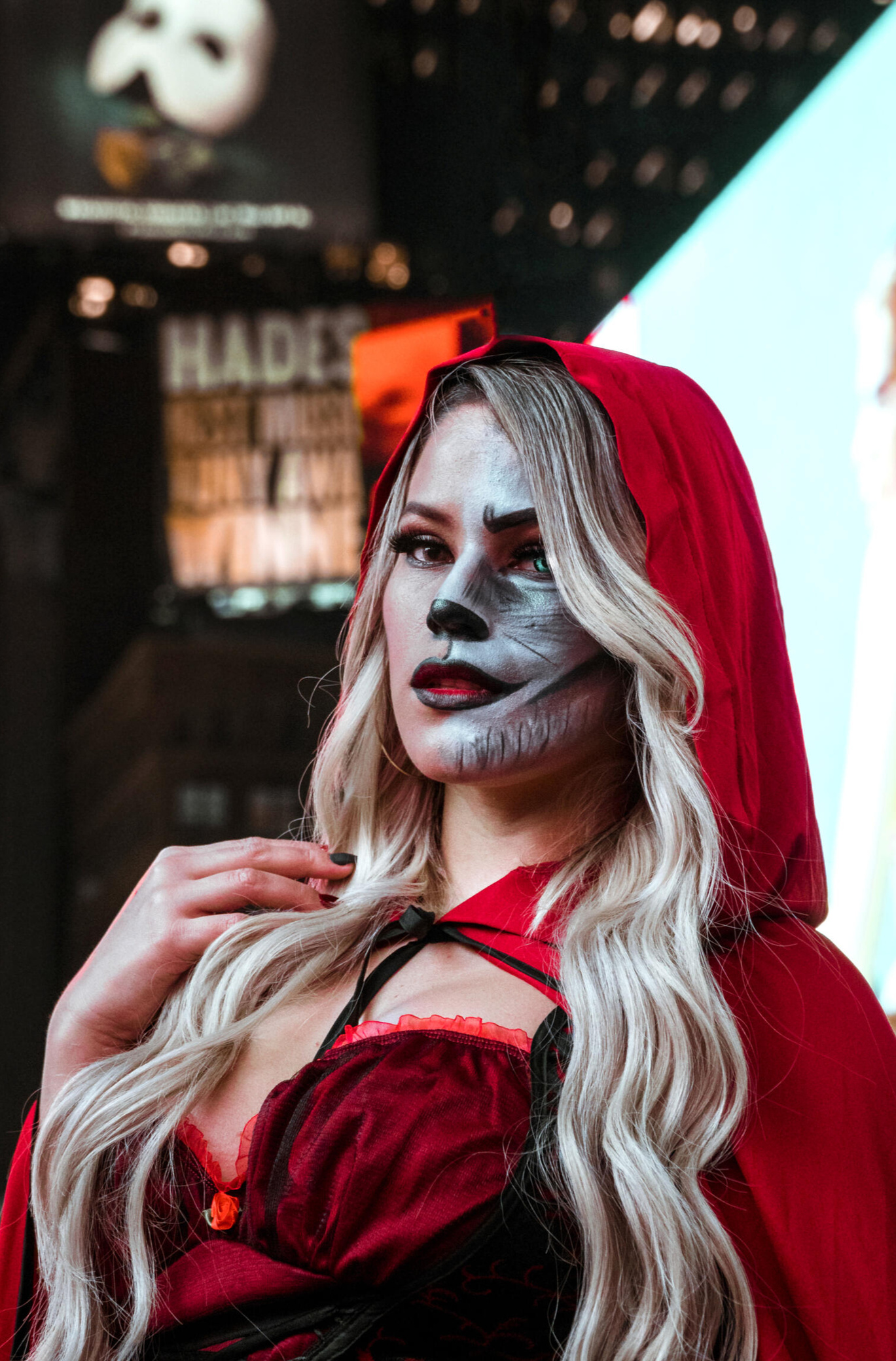 A Halloween fantasy comes to life in Times Square as a woman dressed as Red Riding Hood poses for a portrait, her face half painted to resemble the wolf